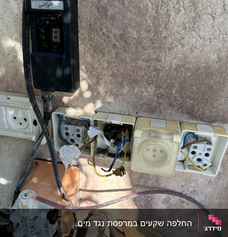 שקעים חשמליים פתוחים עם חוטים חשופים על קיר